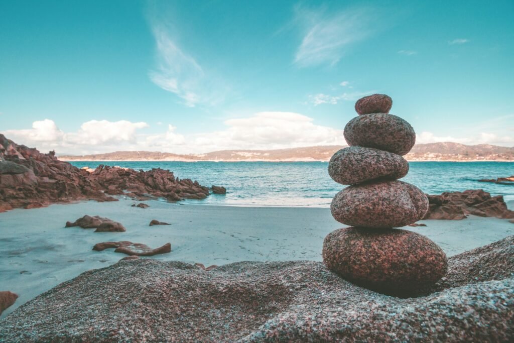 Plage avec la mer et des rochers devant un ciel bleu.