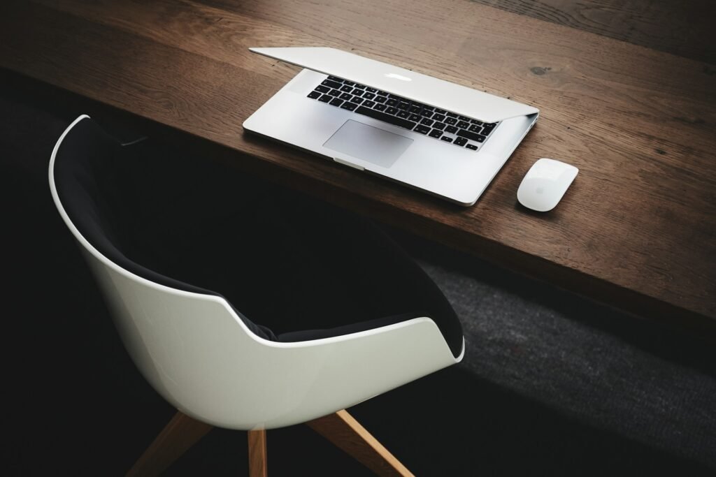 Bureau sombre avec une chaise, un ordinateur et une souris posés dessus.
