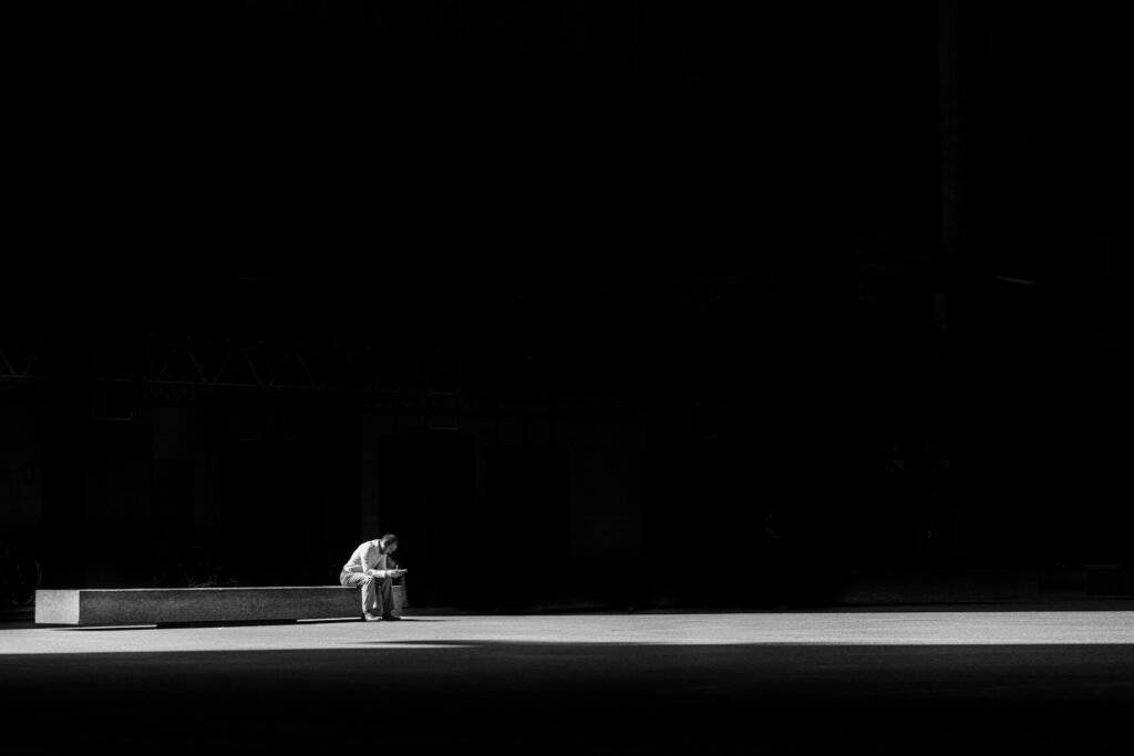 homme assis seul sur un banc dans le noir.