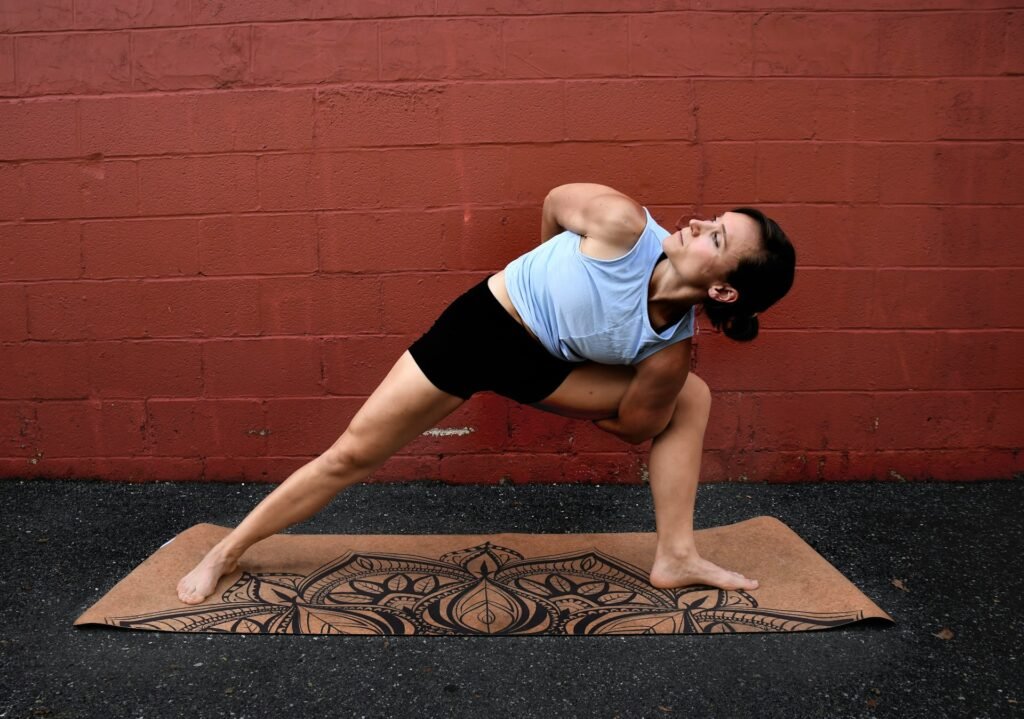 Femme qui fait du yoga sur un tapis en extérieur.