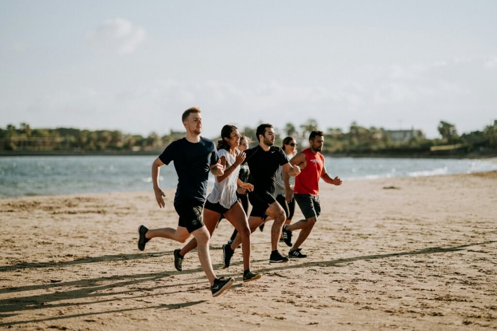 trois hommes et trois femmes en train de courir sur une plage.