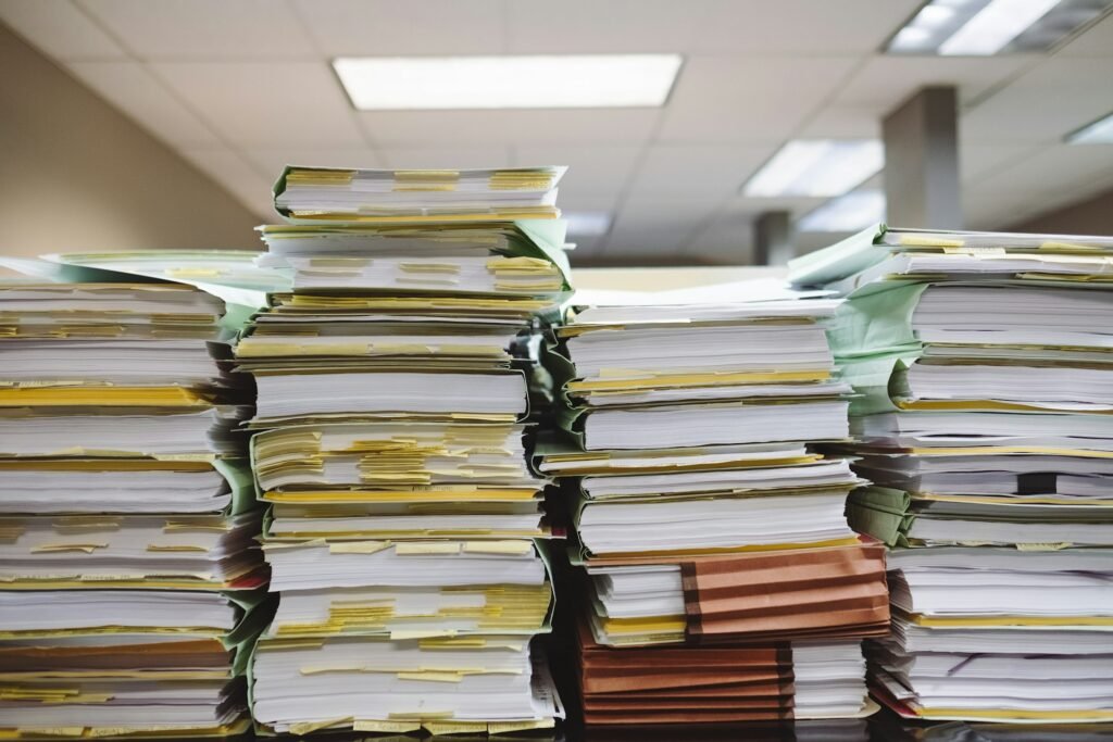Pile de documents, papiers et livres sur un bureau.