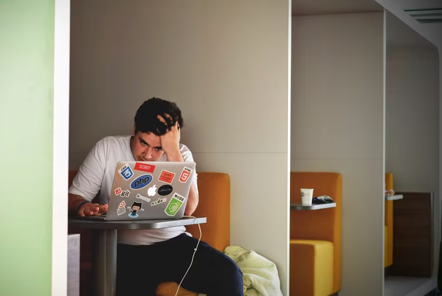 une personne se tenant la tête devant son ordinateur.
